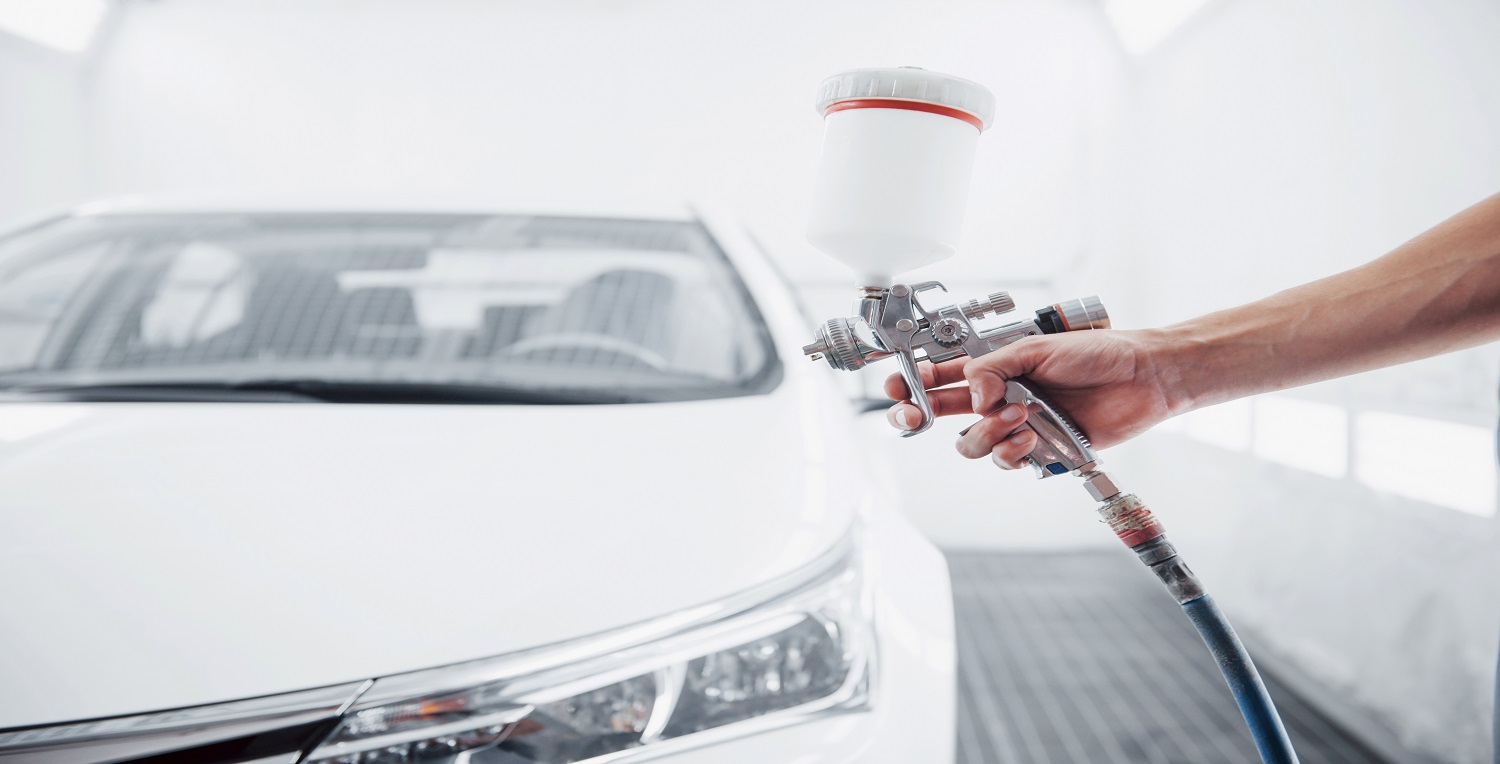 gun with paint in the hands of a man to paint a car.
